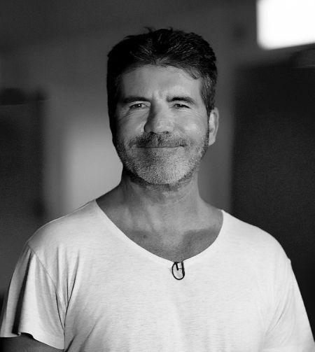 Simon Cowell in a white t-shirt poses for a picture.